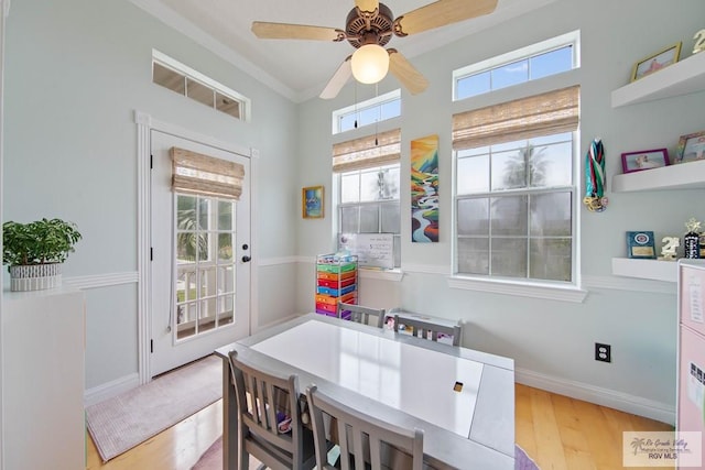 dining space featuring crown molding, wood finished floors, baseboards, and ceiling fan