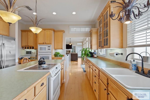 kitchen featuring light brown cabinets, a sink, white appliances, crown molding, and glass insert cabinets