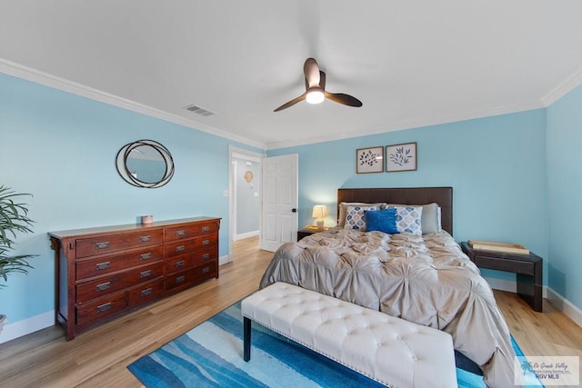 bedroom with visible vents, light wood-style flooring, ornamental molding, baseboards, and ceiling fan