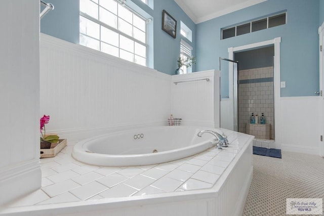 bathroom with a tub with jets, a shower stall, wainscoting, crown molding, and tile patterned floors