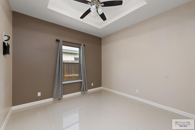 spare room with light tile patterned floors, a raised ceiling, and ceiling fan