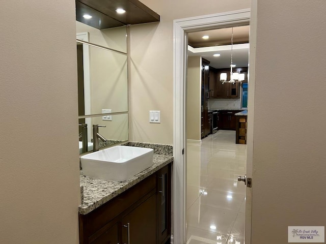 bathroom with vanity, backsplash, and a chandelier