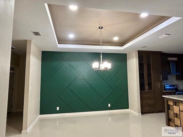 interior space featuring a raised ceiling and a notable chandelier