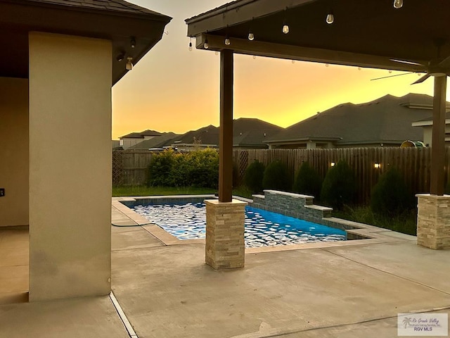 pool at dusk featuring a patio