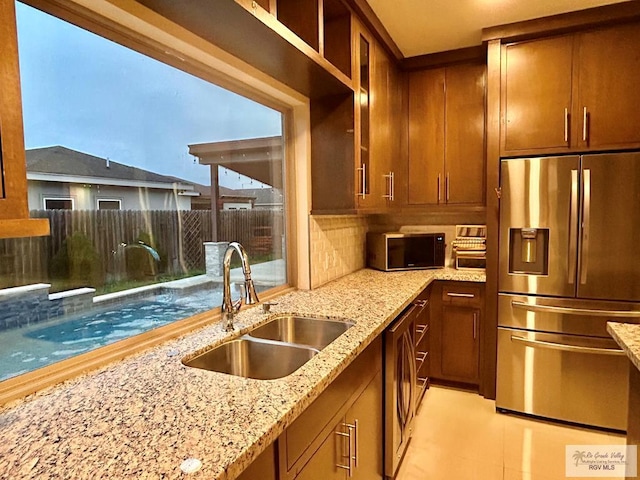 kitchen with sink, tasteful backsplash, stainless steel fridge, light stone countertops, and washer and clothes dryer