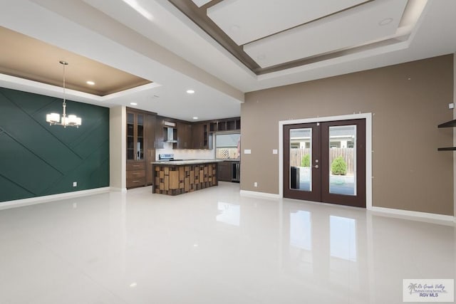 kitchen with pendant lighting, backsplash, a tray ceiling, dark brown cabinets, and french doors