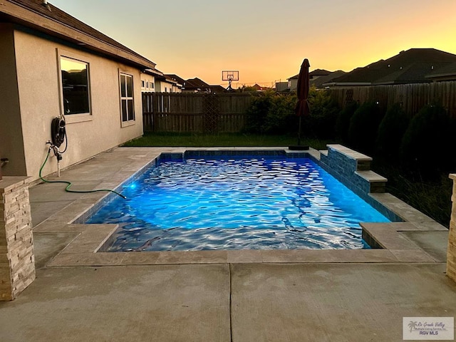 pool at dusk with a patio