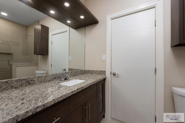 bathroom with vanity, a shower with shower door, and toilet