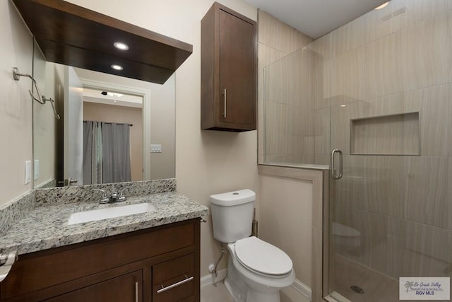 bathroom featuring vanity, toilet, and a shower with door