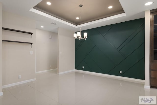 unfurnished room with a raised ceiling, tile patterned flooring, and a chandelier