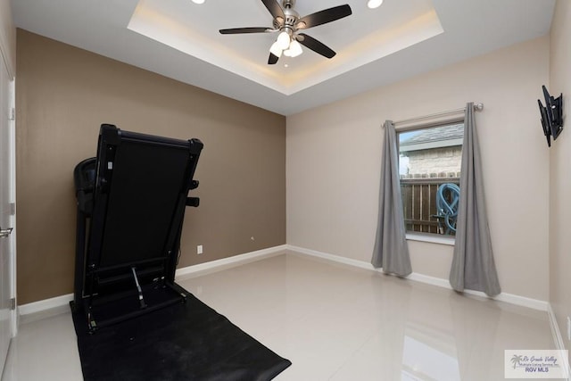 exercise area featuring a raised ceiling and ceiling fan