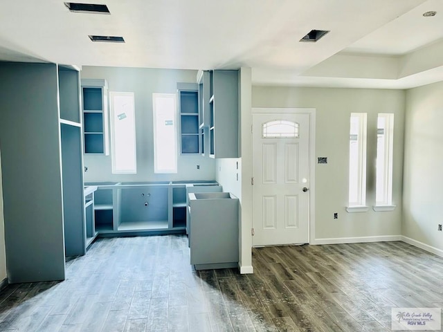 kitchen featuring open shelves, wood finished floors, and baseboards