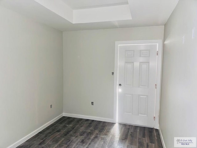 spare room with dark wood-style flooring and baseboards