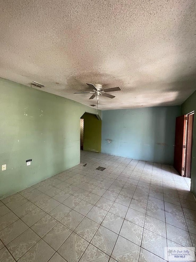 tiled empty room with a textured ceiling and ceiling fan