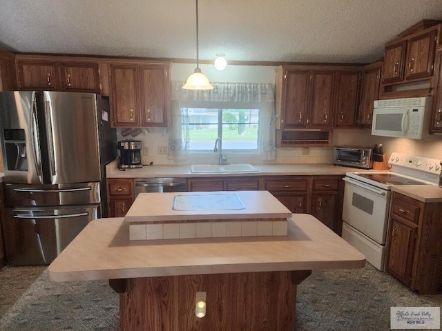 kitchen with a kitchen breakfast bar, a textured ceiling, stainless steel appliances, sink, and a kitchen island