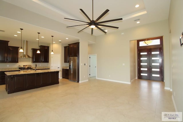 814 Knotty Pine Ln, Harlingen, TX 78552 - kitchen with stainless steel appliances, wall chimney range hood, open floor plan, a ceiling fan, and dark brown cabinets
