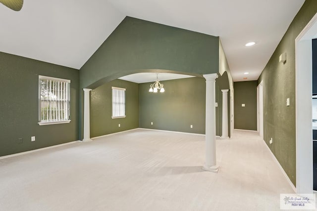 empty room featuring a wealth of natural light, light carpet, lofted ceiling, and a notable chandelier