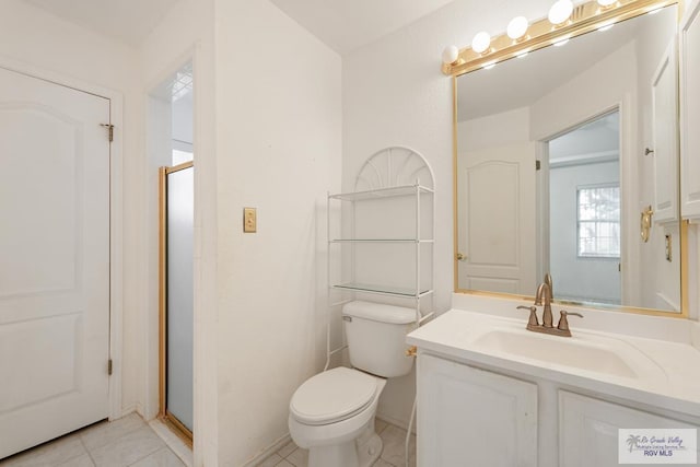 bathroom featuring toilet, vanity, tile patterned floors, and a shower with shower door