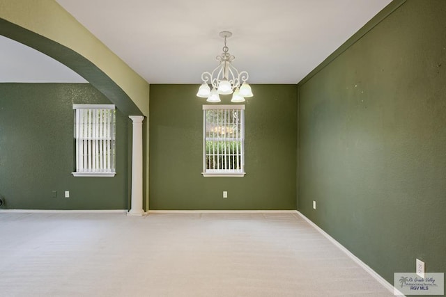 empty room featuring a chandelier and ornate columns