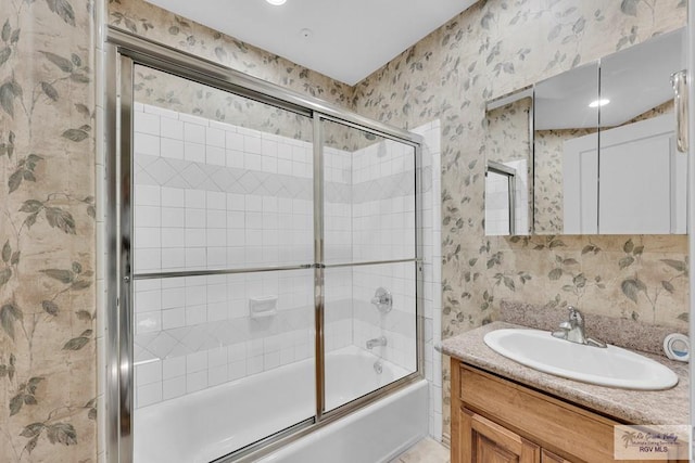 full bath with shower / bath combination with glass door, vanity, and wallpapered walls