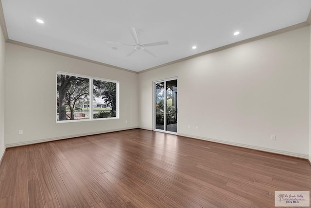 spare room with a ceiling fan, wood finished floors, baseboards, and ornamental molding