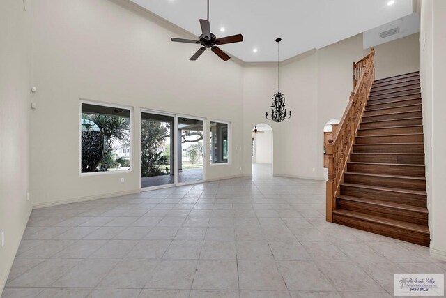 unfurnished living room featuring arched walkways, visible vents, stairs, and a ceiling fan