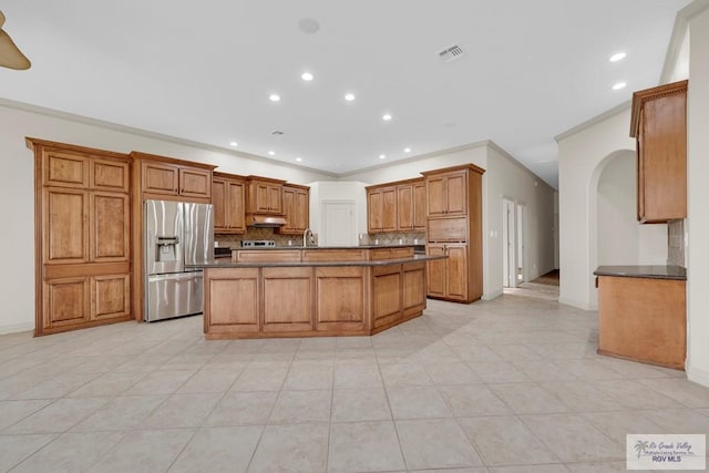 kitchen with under cabinet range hood, visible vents, dark countertops, and stainless steel fridge with ice dispenser