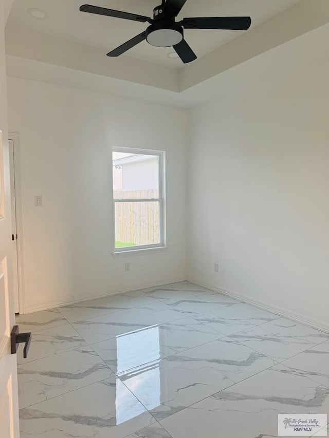 1321 White Oak Dr, Harlingen, TX 78522 - spare room with light marble finish floors, baseboards, ceiling fan, and a tray ceiling