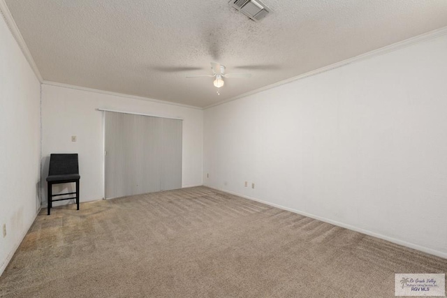 carpeted spare room with ceiling fan, a textured ceiling, and ornamental molding