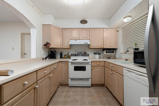 kitchen with kitchen peninsula, white appliances, a textured ceiling, sink, and light brown cabinets