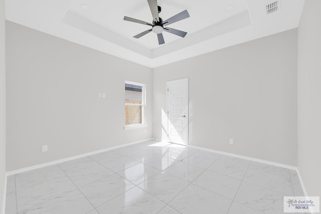 spare room featuring a tray ceiling and ceiling fan