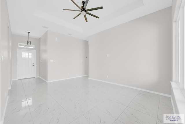 interior space with ceiling fan and a tray ceiling