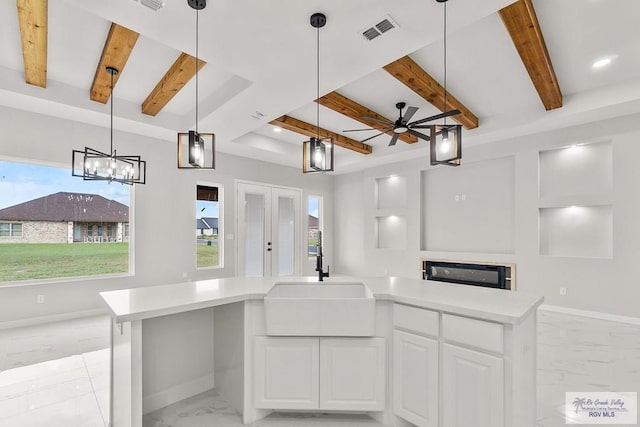 kitchen with ceiling fan, sink, a kitchen island, decorative light fixtures, and white cabinets