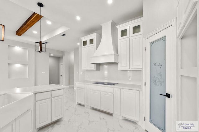 kitchen featuring black electric stovetop, white cabinets, decorative light fixtures, and custom range hood