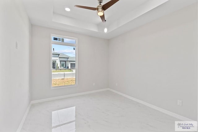 empty room featuring ceiling fan and a tray ceiling