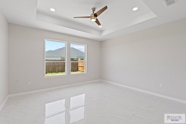 empty room featuring ceiling fan and a tray ceiling