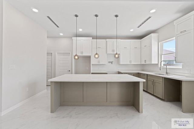 kitchen featuring decorative light fixtures, a center island, white cabinetry, and sink