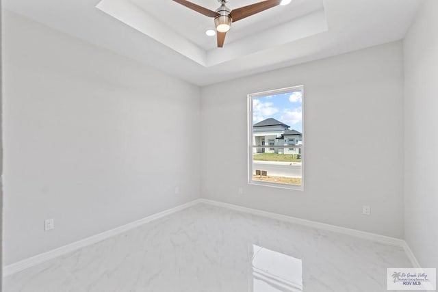 empty room with a raised ceiling and ceiling fan