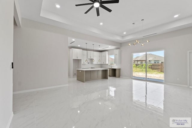 unfurnished living room featuring a tray ceiling and ceiling fan