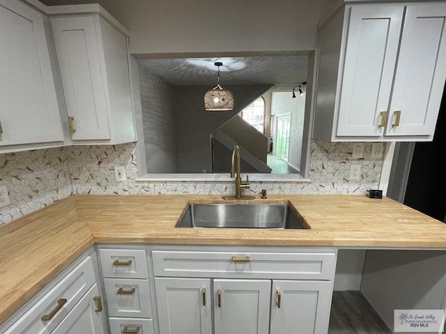 kitchen with backsplash, dark wood-type flooring, sink, pendant lighting, and white cabinets