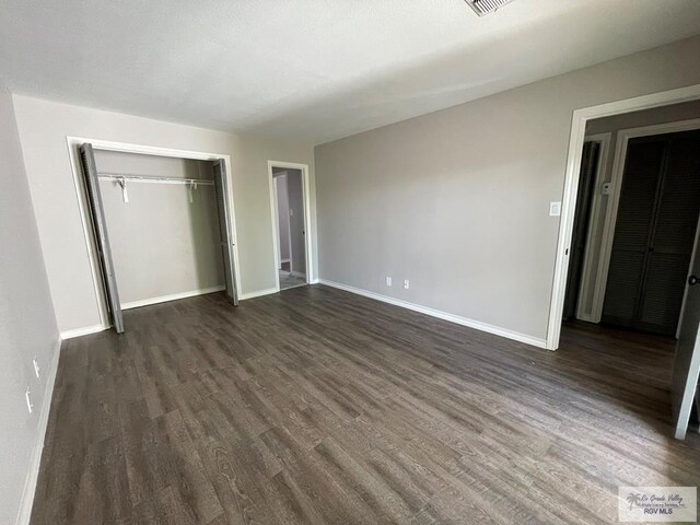 unfurnished bedroom with dark wood-type flooring and a closet