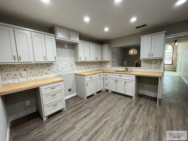 kitchen with butcher block countertops, dark wood-type flooring, pendant lighting, and sink