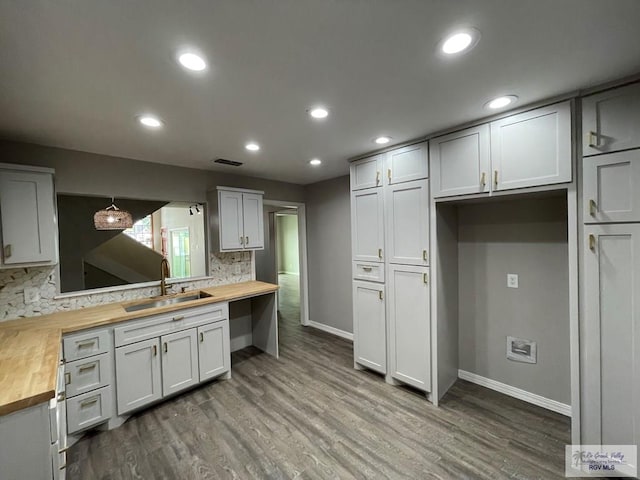 kitchen featuring decorative backsplash, sink, decorative light fixtures, and wood counters