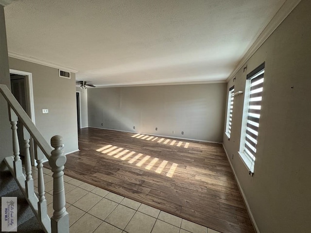 empty room featuring ornamental molding, a textured ceiling, ceiling fan, and light hardwood / wood-style floors