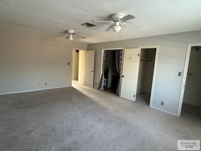 unfurnished bedroom with multiple closets, light colored carpet, and ceiling fan