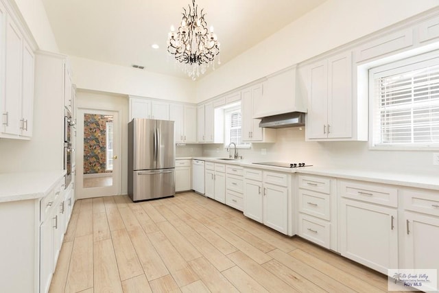 kitchen featuring sink, white cabinetry, hanging light fixtures, stainless steel appliances, and custom exhaust hood