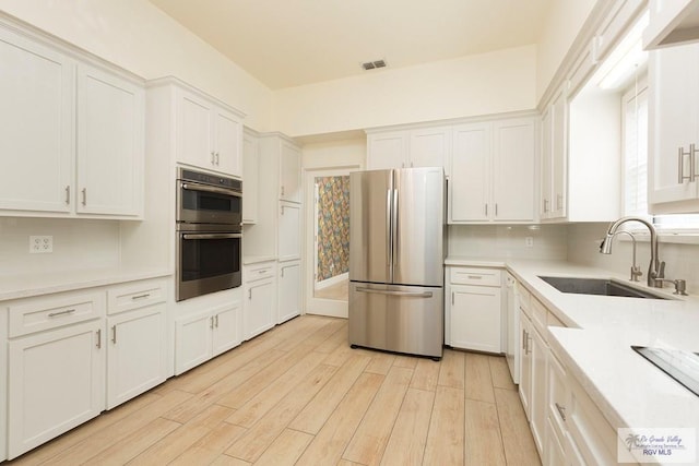 kitchen featuring white cabinetry, sink, stainless steel appliances, and light wood-type flooring