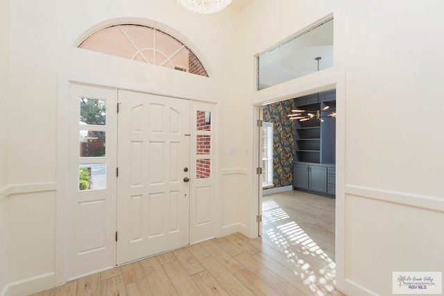 foyer entrance with a chandelier and light wood-type flooring