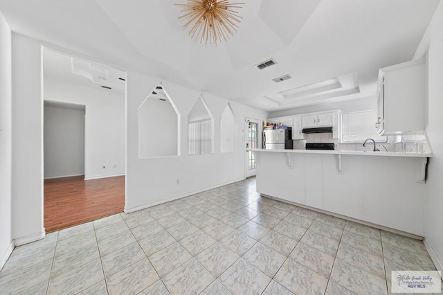 4217 W Ithaca Ave, Mcallen, TX 78501 - kitchen with freestanding refrigerator, under cabinet range hood, a raised ceiling, a peninsula, and light countertops