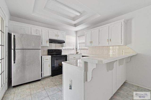 4217 W Ithaca Ave, Mcallen, TX 78501 - kitchen featuring freestanding refrigerator, black range with electric stovetop, under cabinet range hood, a peninsula, and a raised ceiling
